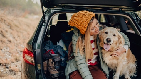 Vrouw knuffelt met golden retriever hond in koffer van de auto